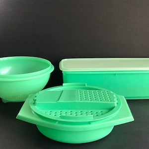 May include: A set of three green plastic kitchen containers. The set includes a large rectangular container with a lid, a round bowl with a strainer, and a round bowl with a grater insert.