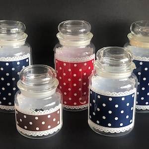 May include: Five glass jars with clear glass lids. Each jar features a decorative band with white polka dots on a navy blue, red, or brown background. A white lace trim borders the band on each jar.