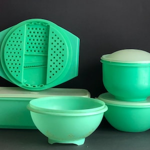 May include: Set of six vintage green plastic kitchen bowls and containers. The set includes a colander with a built-in grater, a rectangular container with a lid, and three round bowls with lids.