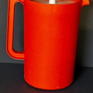 Könnte beinhalten: Eine weiße Keramik-Tasse mit schwarzem Henkel und dem Text "But First, Coffee" in schwarzer, fetter Schrift. Die Tasse steht auf einer weißen Oberfläche. Die Tasse ist etwa 10 cm hoch.