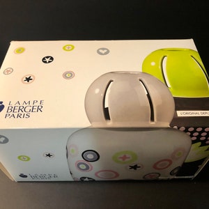 May include: A Lampe Berger Paris fragrance diffuser in its original packaging. The diffuser is light gray with a spherical top and a patterned base. The box is white with colorful geometric shapes and the brand logo.