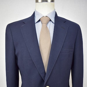 May include: A navy blue blazer with a single gold button closure. The blazer has a classic fit and a notched lapel.