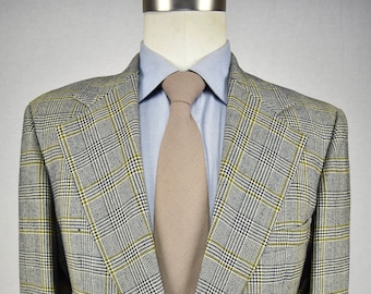 May include: A gray, black, and yellow plaid blazer with a single button closure. The blazer has a notched lapel and a brown tie.