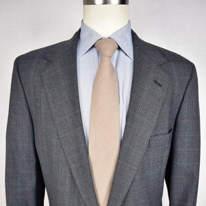 May include: A gray plaid blazer with a single button closure and a light blue shirt with a beige tie.