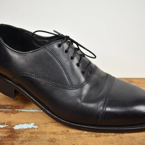 May include: Black leather lace-up dress shoes with a cap toe.