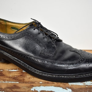 May include: Black leather oxford shoes with a wingtip design and a lace-up closure.