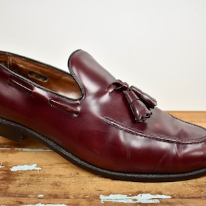 May include: A pair of burgundy leather tassel loafers with a black leather sole.