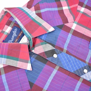 May include: A red, blue, purple, and green plaid button-up shirt with a white collar. The shirt has a label that reads "Wrangler" and "Size 14 1/2 - 34/36".