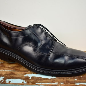 Puede incluir: Zapatos de vestir negros de cuero con cordones, punta redonda y tacón ligeramente elevado.