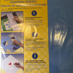 May include: A Dritz Quilting 3-Way Sandboard measuring 12.5 inches by 12.5 inches. The yellow packaging features three numbered sections illustrating a textured surface for marking, a felt surface for design, and a white laminate surface for tracing.