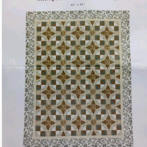 May include: A North Star Gold Quilt Kit by Monique Dillard, featuring Boundless Home for the Holidays. The quilt design is a repeating pattern of gold and teal star shapes on a cream background, with a floral border. The quilt measures 66" x 84".