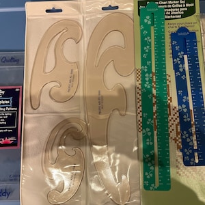 May include: A set of quilting tools including a clear plastic template for creating curved lines, a green and blue ruler with shamrock designs, and a clear plastic template for creating circle slices. The tools are packaged in plastic bags and labeled with the brand name "Fun & Done! Quilting".