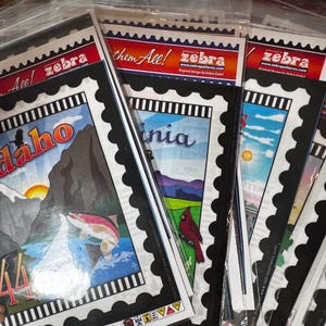 Puede incluir: Una colección de postales coloridas con temática estatal con bordes negros y bordes festoneados. Las postales presentan ilustraciones de varios estados, incluidos Idaho, Virginia y otros. Las postales están etiquetadas con el nombre del estado y un número. El texto "Collect them All!" y "zebra" está impreso en la parte superior de las postales.