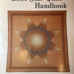 May include: A book titled "The Lone Star Quilt Handbook" with a brown and beige quilt design on the cover. The text "A new, easier way to make one of America's best loved quilts" is below the quilt design. The author's name, "Blanche Young", is at the bottom of the cover.