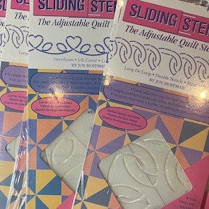 May include: Three packages of quilting stencils with a pink background and white lettering. The stencils are for creating a heart, loop, and double loop design. The text on the package reads "Sliding Stencil, The Adjustable Quilt Stencil, Sweetheart, Joli-Coeur, Coeur, by Joy Hoffman, Loop De Loop, Double Boucle, Rizar en, Easily adjusts to any size quilt border, Corner design included, Use stencil as shown or adjust to create your own designs".