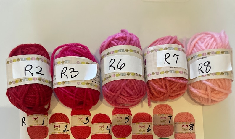 May include: Eight balls of yarn in various shades of pink and red, labeled R1 through R8.
