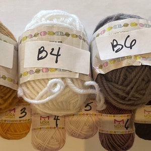 May include: Four balls of yarn in different colors: beige, white, gray, and black. Each ball has a label with a letter and number, B3, B4, B6, and B7.
