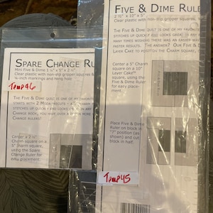 Könnte beinhalten: Zwei transparente Kunststoff-Nähregeln mit rutschfesten Griffleisten. Die Five & Dime Regel ist 6,35 cm x 25,4 cm x 12,7 cm groß. Die Spare Change Regel ist 3,175 cm x 12,7 cm x 5,08 cm groß. Beide Regeln haben Markierungen und Aufhängelöcher. Der Text "Temp 46" und "Temp 45" ist auf den Regeln geschrieben.