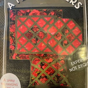 May include: A quilting pattern featuring a red and green floral design. The pattern includes instructions for making a wall hanging, euro pillow, and table topper. The text on the pattern reads "A Few Pointers" and "Wallhanging, Euro Pillow & Tabletopper".