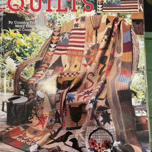 May include: A book titled "Garden Club Quilts" by Country Threads, Inc., Mary Etherington and Connie Tusone. The cover features a patchwork quilt with a variety of colors and patterns, including stars, flowers, and birds. The quilt is draped over a wooden chair on a porch.