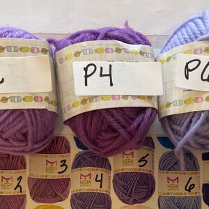 May include: Eight balls of yarn in different colors, labeled P1, P2, P4, P6, and P7. The yarn is arranged in a row on a white surface.