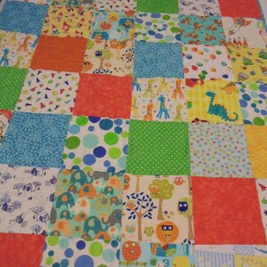 May include: A colorful patchwork quilt with a variety of animal and geometric patterns. The quilt is made up of squares of different fabrics, including blue, green, orange, and yellow. The quilt is perfect for a baby's nursery or a child's bedroom.