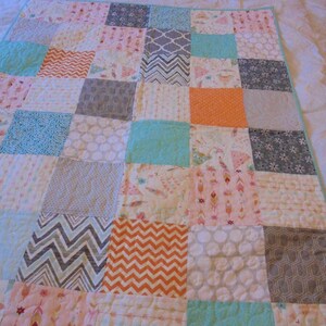 May include: A patchwork quilt with a variety of patterns and colors, including gray, orange, pink, and turquoise.