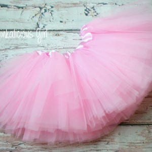 K&ouml;nnte beinhalten: Ein rosa T&uuml;ll-Tutu mit einem Satin-Bund. Das Tutu ist geschichtet und flauschig, perfekt f&uuml;r ein kleines M&auml;dchen zum Verkleiden.