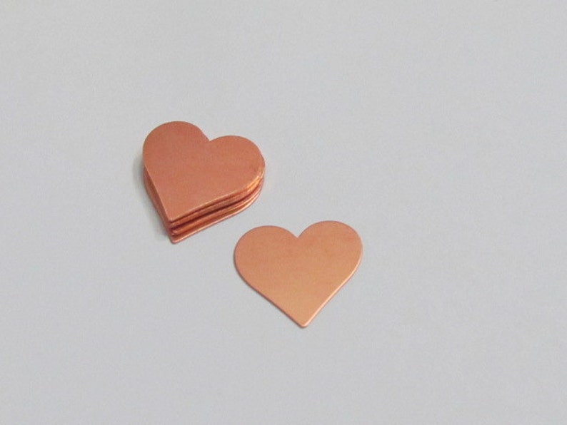 Puede incluir: Una pila de cinco planchas de metal en forma de coraz&oacute;n de cobre. Los corazones miden aproximadamente 5 cm de ancho y 5 cm de alto.