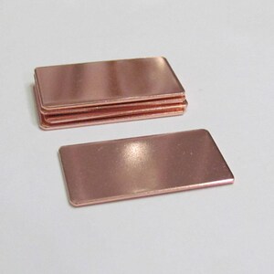 May include: A stack of four rectangular copper sheets. The sheets are smooth and have a shiny, metallic finish.