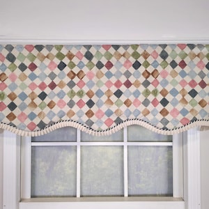 May include: A window valance featuring a repeating diamond pattern in muted shades of pink, blue, green, and brown. The fabric has a scalloped bottom edge finished with a decorative cream-colored fringe trim with a black twisted cord detail.