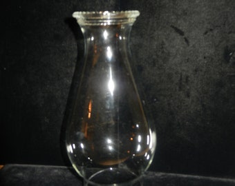 May include: A clear glass lamp chimney with a rounded bottom and a flared top.