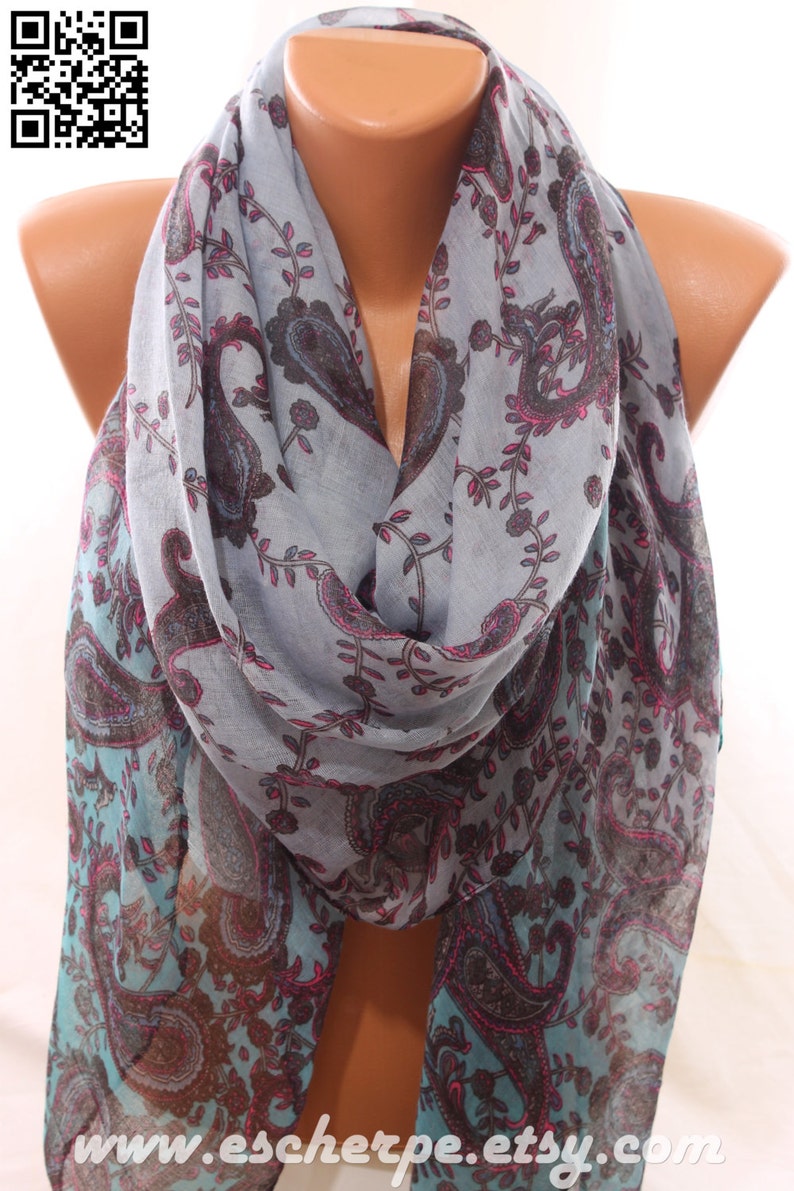 May include: A light blue scarf with a paisley pattern in shades of brown, pink, and teal. The scarf is draped around a mannequin's neck.