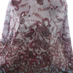 May include: A sheer scarf with a paisley pattern in shades of gray, brown, and pink. The scarf has a gradient effect, fading to a teal color at the bottom. The text "www.escherpe.etsy.com" is printed on the bottom of the scarf.