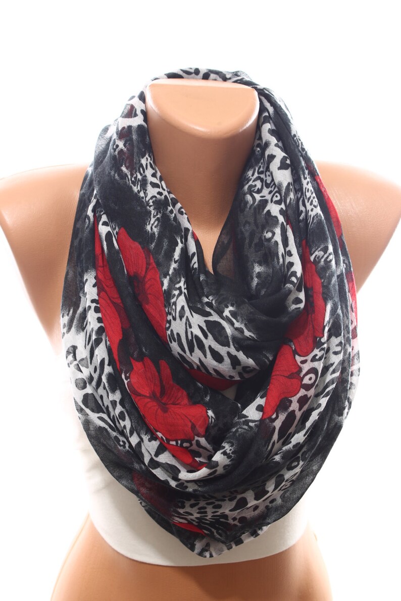 Puede incluir: Una bufanda de estampado de leopardo blanco y negro con detalles florales rojos. La bufanda est&aacute; hecha de una tela ligera y es perfecta para agregar un toque de estilo a cualquier atuendo.
