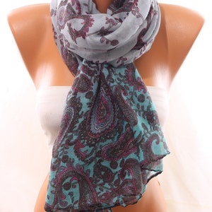 May include: A gray and teal paisley patterned scarf with a light gray background. The scarf is folded and draped over a mannequin.