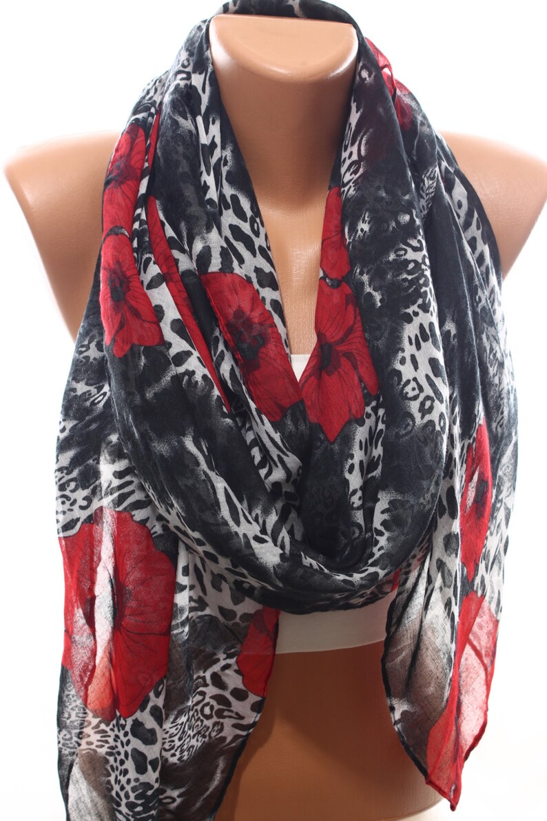 Puede incluir: Una bufanda de estampado de leopardo negro y blanco con detalles florales rojos. La bufanda est&aacute; hecha de una tela ligera y es perfecta para agregar un toque de estilo a cualquier atuendo.