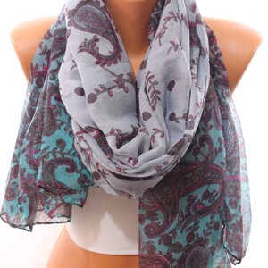 May include: A gray and teal paisley patterned scarf with pink accents. The scarf is folded and draped around a mannequin's neck.