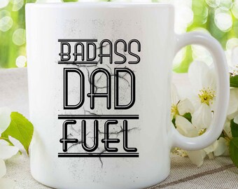 May include: White ceramic coffee mug with black text that reads "Badass Dad Fuel".
