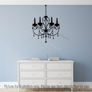 May include: Black silhouette of a chandelier with a decorative design and hanging crystals. The chandelier is on a light blue wall above a white dresser.