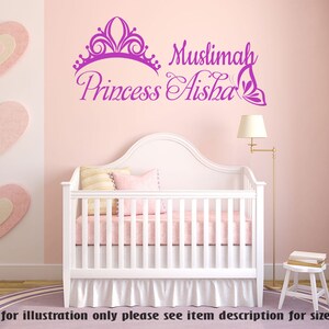 May include: Purple vinyl wall decal with a crown, butterfly, and the text "Muslimah Princess Aisha". The decal is displayed on a pink wall above a white crib with a pink and white bedding set.