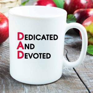 May include: White ceramic mug with the words "DAD" in red and "DEDICATED AND DEVOTED" in black.