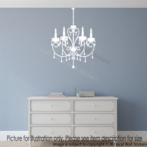 May include: White silhouette of a chandelier with a decorative design and hanging crystals. The chandelier is on a light blue wall with a white dresser underneath.