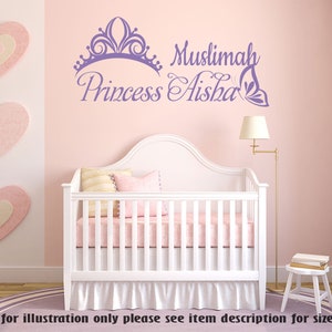 May include: Purple and white wall decal with a crown, butterfly, and the text "Muslimah Princess Aisha". The decal is on a pink wall above a white crib with a pink and white bedding set.