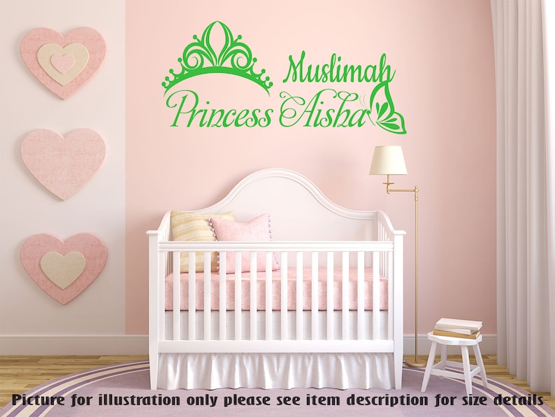 May include: Green vinyl wall decal with a crown, the words "Muslimah Princess Aisha" and a butterfly design. The decal is displayed on a pink wall above a white crib.