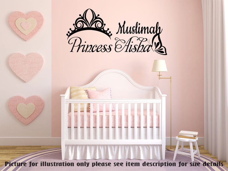 May include: A pink nursery with a white crib and a wall decal that says "Muslimah Princess Aisha" with a crown and butterfly design.