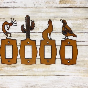 May include: Set of five rustic metal light switch covers featuring southwestern designs. The designs include a cactus, a coyote, a quail, and a traditional Native American dancer. The covers are a rusty brown color.