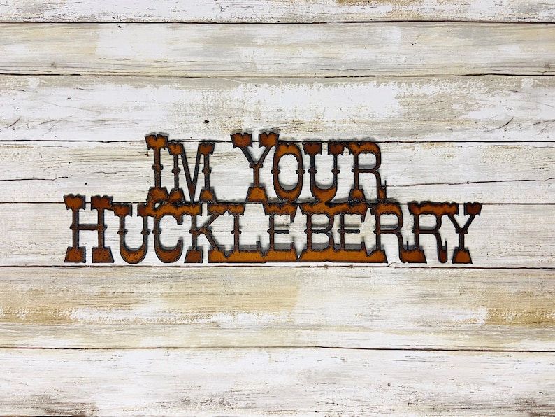 May include: Rustic wooden sign with the text "I'm your huckleberry" in rusty metal letters.