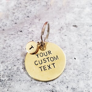 May include: A gold-toned keychain with a round tag that says "YOUR CUSTOM TEXT". A smaller round tag with the letter "T" is attached to the keychain.