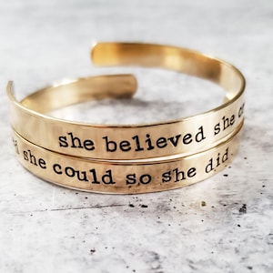 May include: Gold-toned bracelet with the inscription "She believed she could so she did."